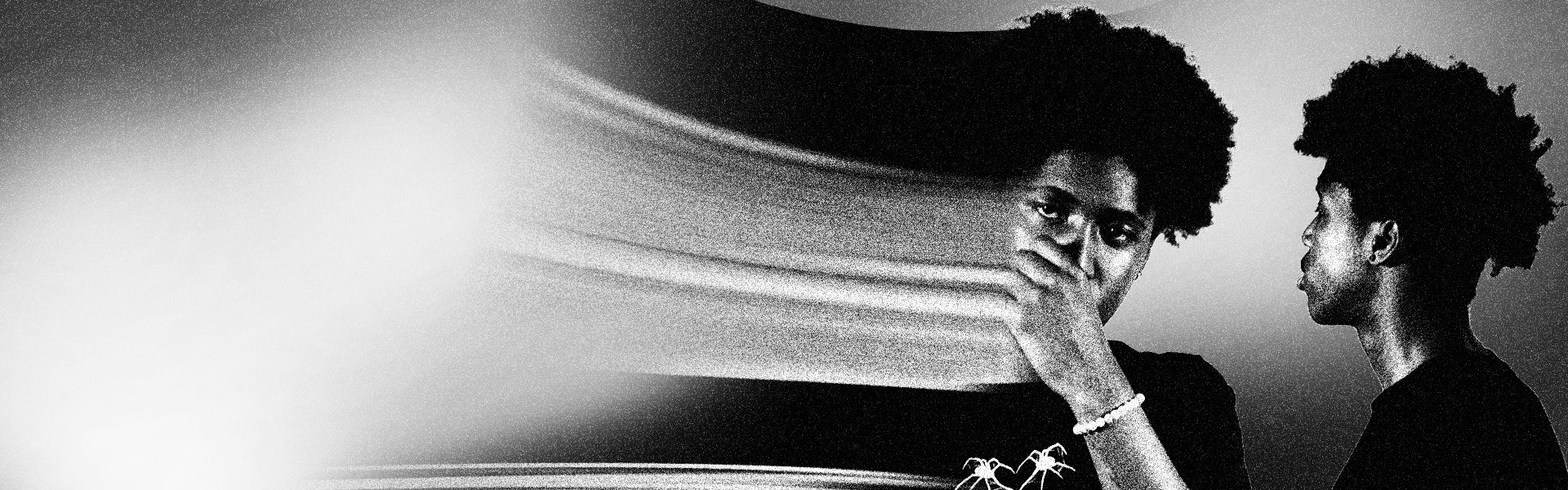 Black-and-white image of one individual with curly hair in a dynamic pose, one in close-up with hand near face, the other in thoughtful profile, set against a blurred, streaked background. The gritty, high-contrast aesthetic conveys creativity, innovation, and forward-thinking energy